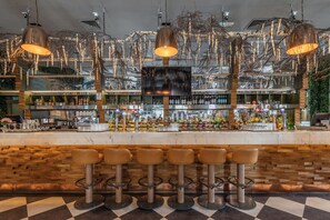 A bar area with a checkered floor, multiple stools, and a variety of bottles and glasses on the shelves. - Sir Thomas Hotel (Liverpool)