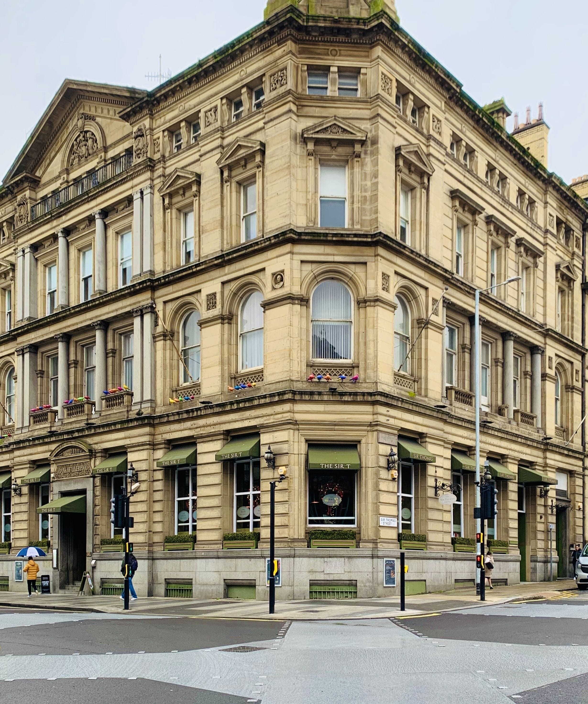 Un edificio histórico con arquitectura ornamentada, múltiples ventanas y toldos verdes.