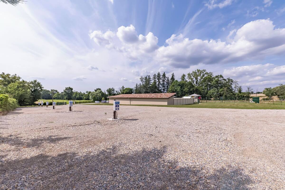 A gravel parking area with a building in the background.