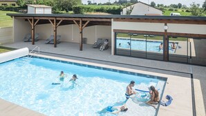 A swimming pool with people swimming and lounging. There are lounge chairs and a covered area with a view of the pool. - Le Moulin de la Brevette (Arbigny)