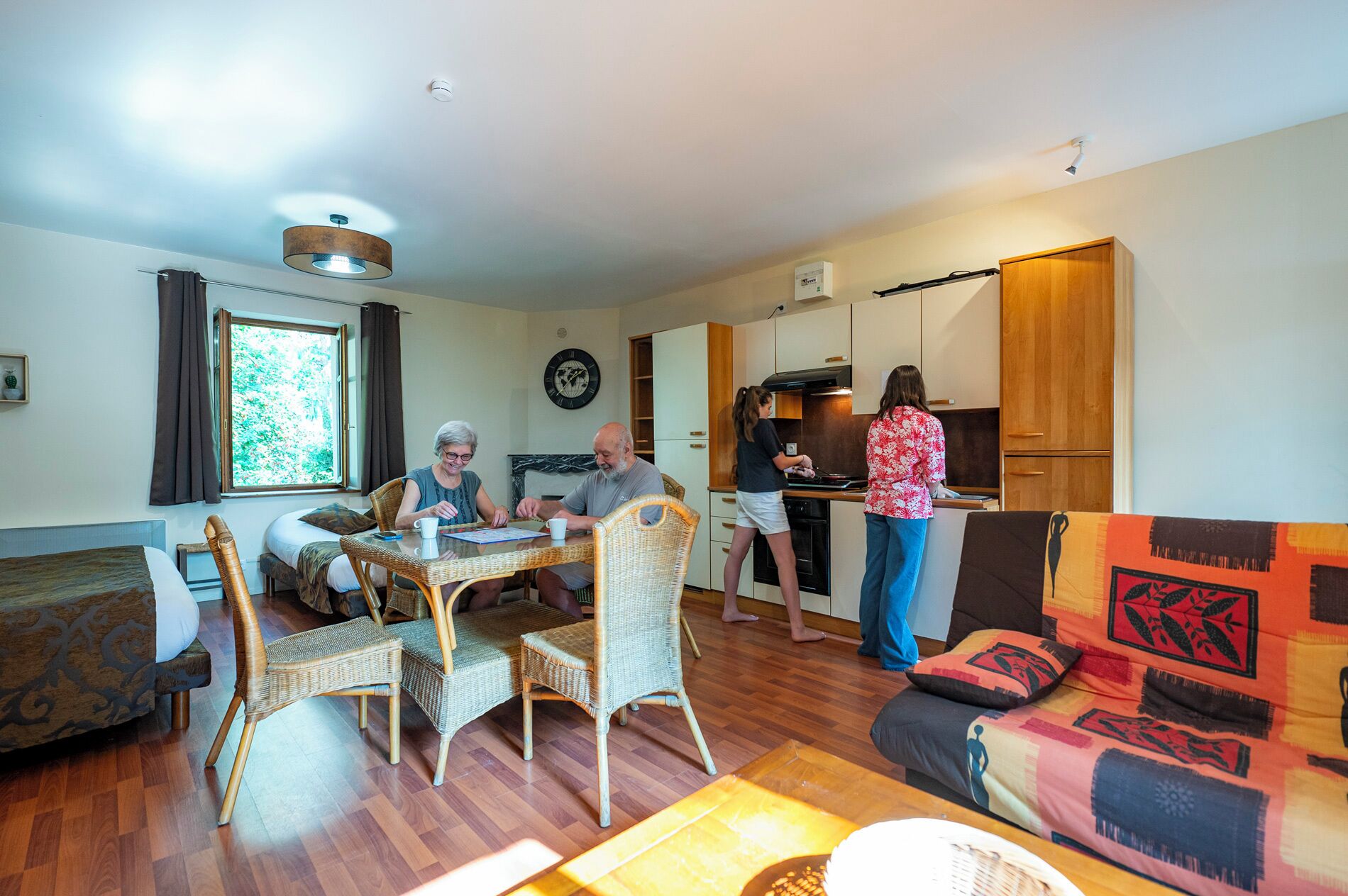 A cozy living room with a dining area, a kitchen, and a sofa with patterned cushions.