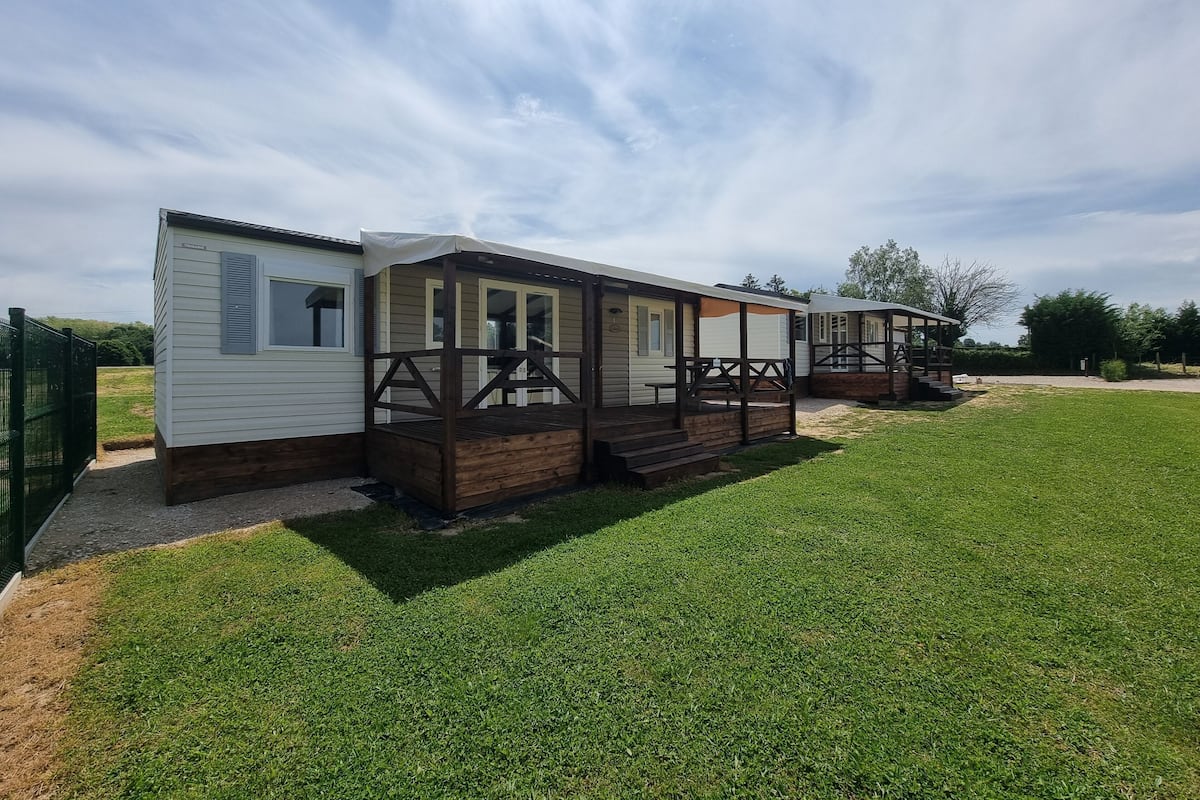 A row of mobile homes with wooden decks and a grassy yard.
