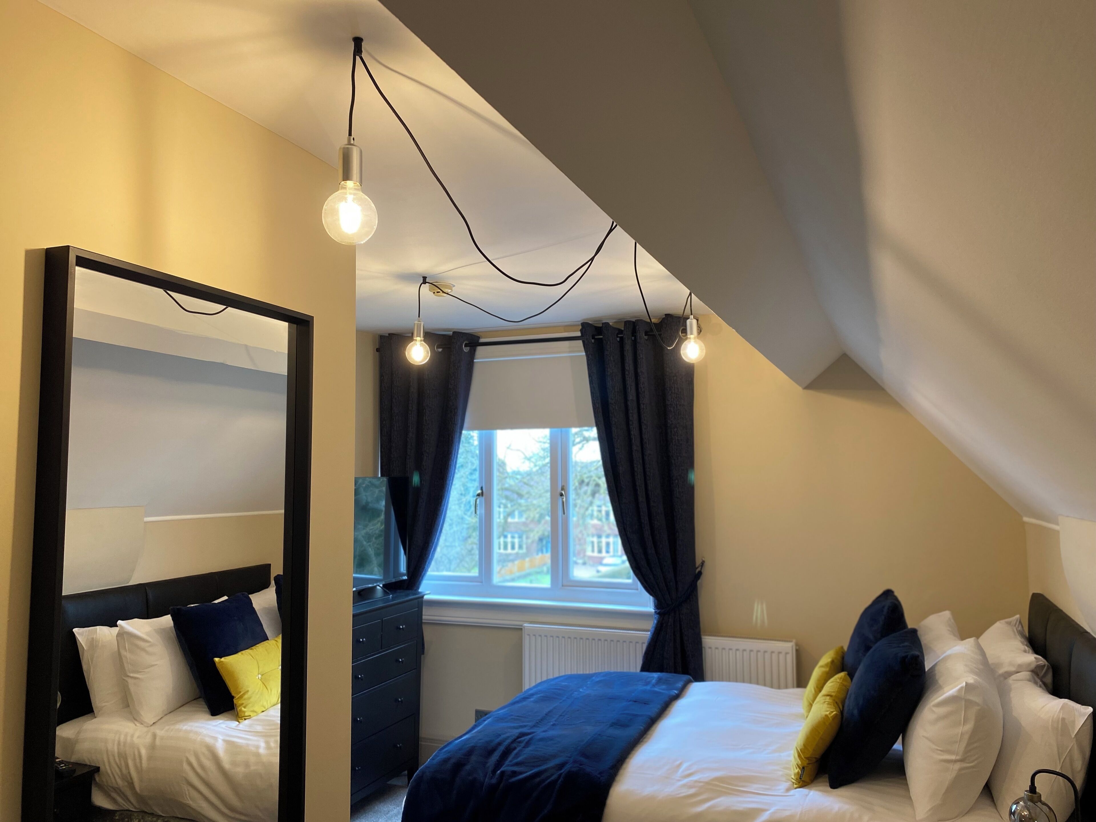Une chambre à coucher moderne avec un lit, une commode et un grand miroir.