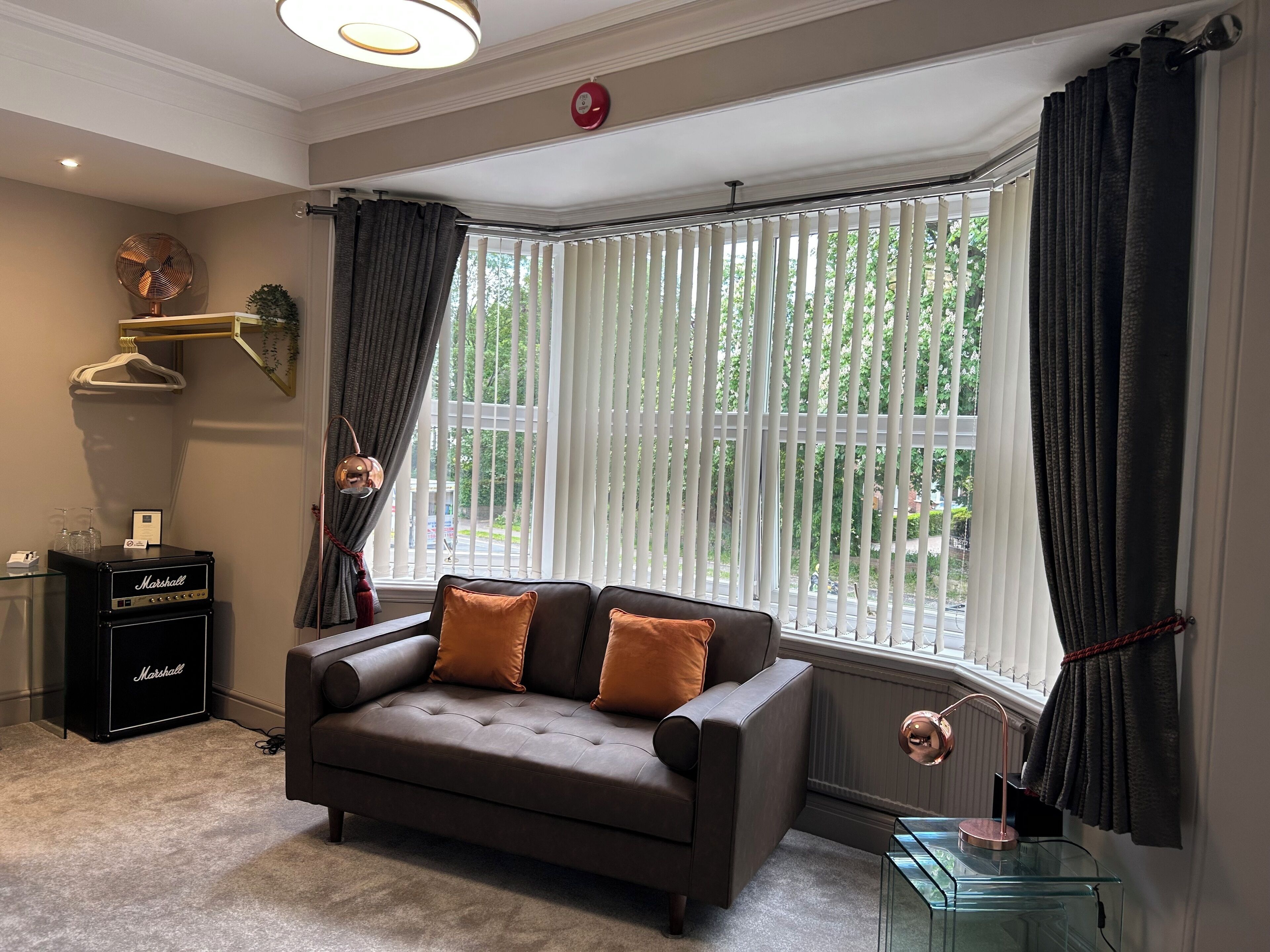 A modern living room with a brown sofa, a Marshall amplifier, and a glass coffee table.