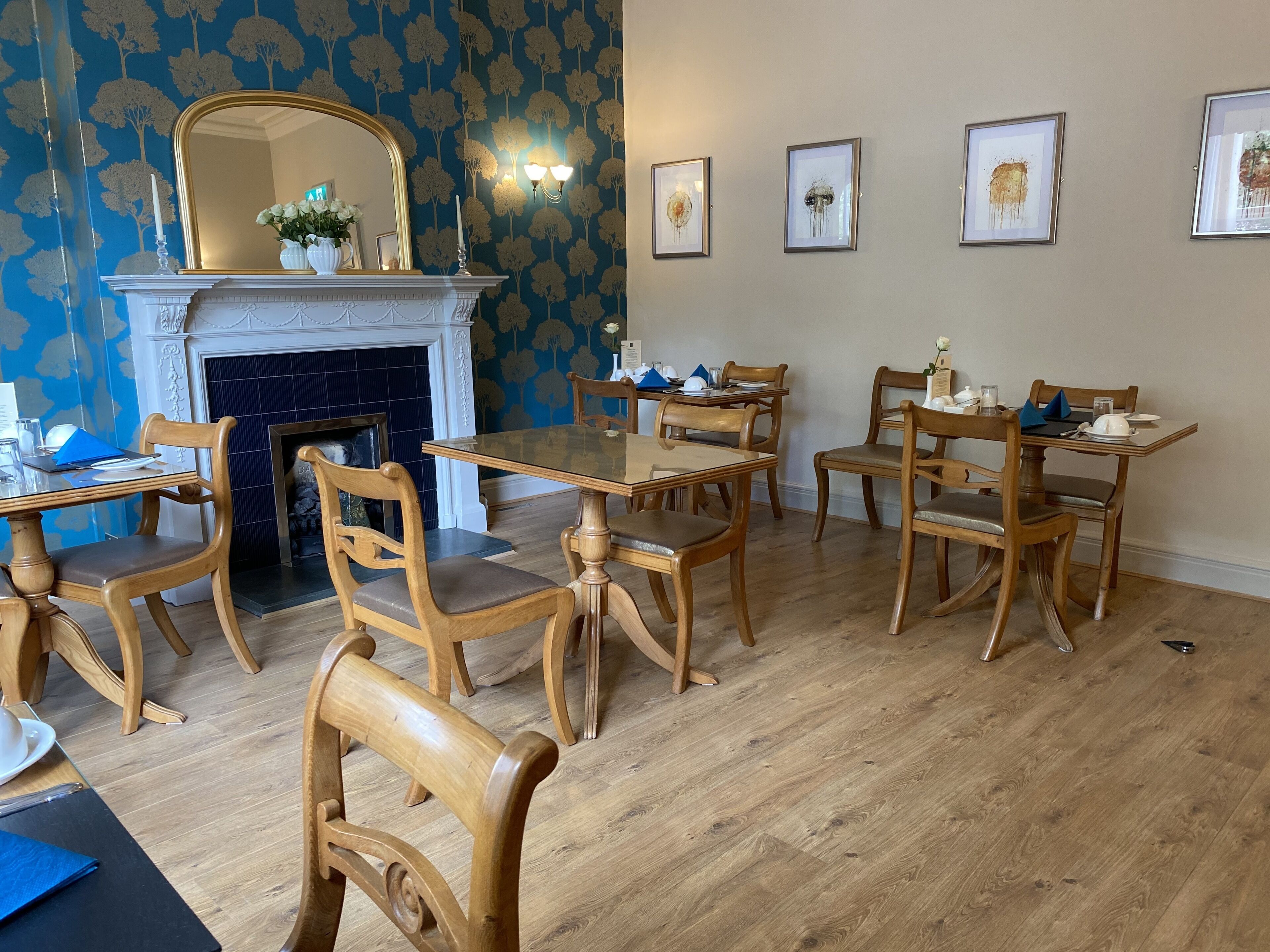 A dining area with wooden chairs and tables, a fireplace, and wall-mounted artwork.