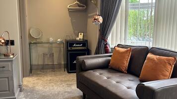 Una sala de estar moderna con un sofá de cuero, un escritorio de vidrio y un amplificador Marshall.