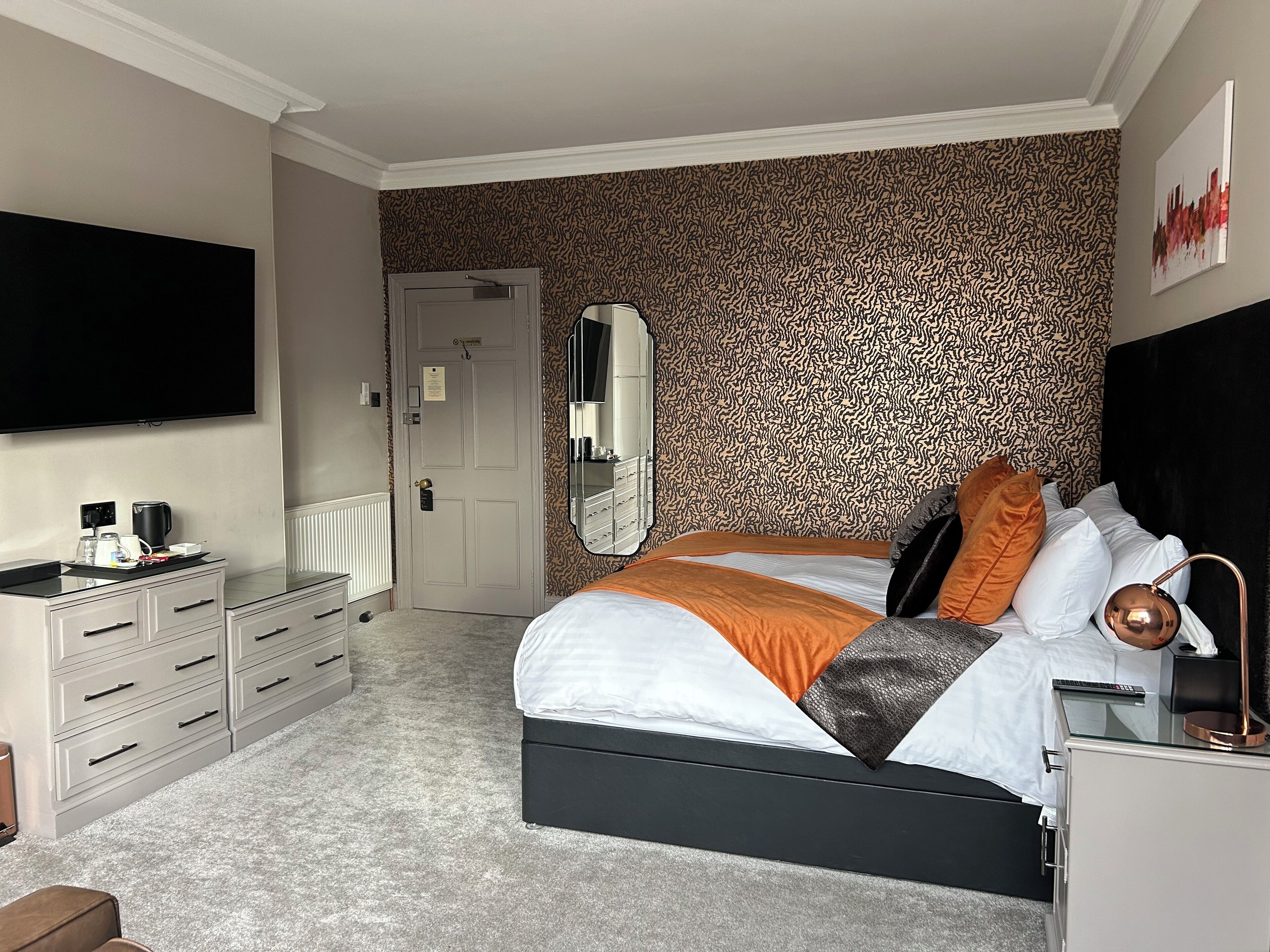 Une chambre moderne avec un lit, une commode et un téléviseur à écran plat.