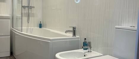 Un baño moderno con una bañera independiente, un bidé y un inodoro.
