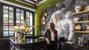 A room with a black bar counter, a large window, and a wall with a black and white mural. - Hôtel Louis II  (Paris)