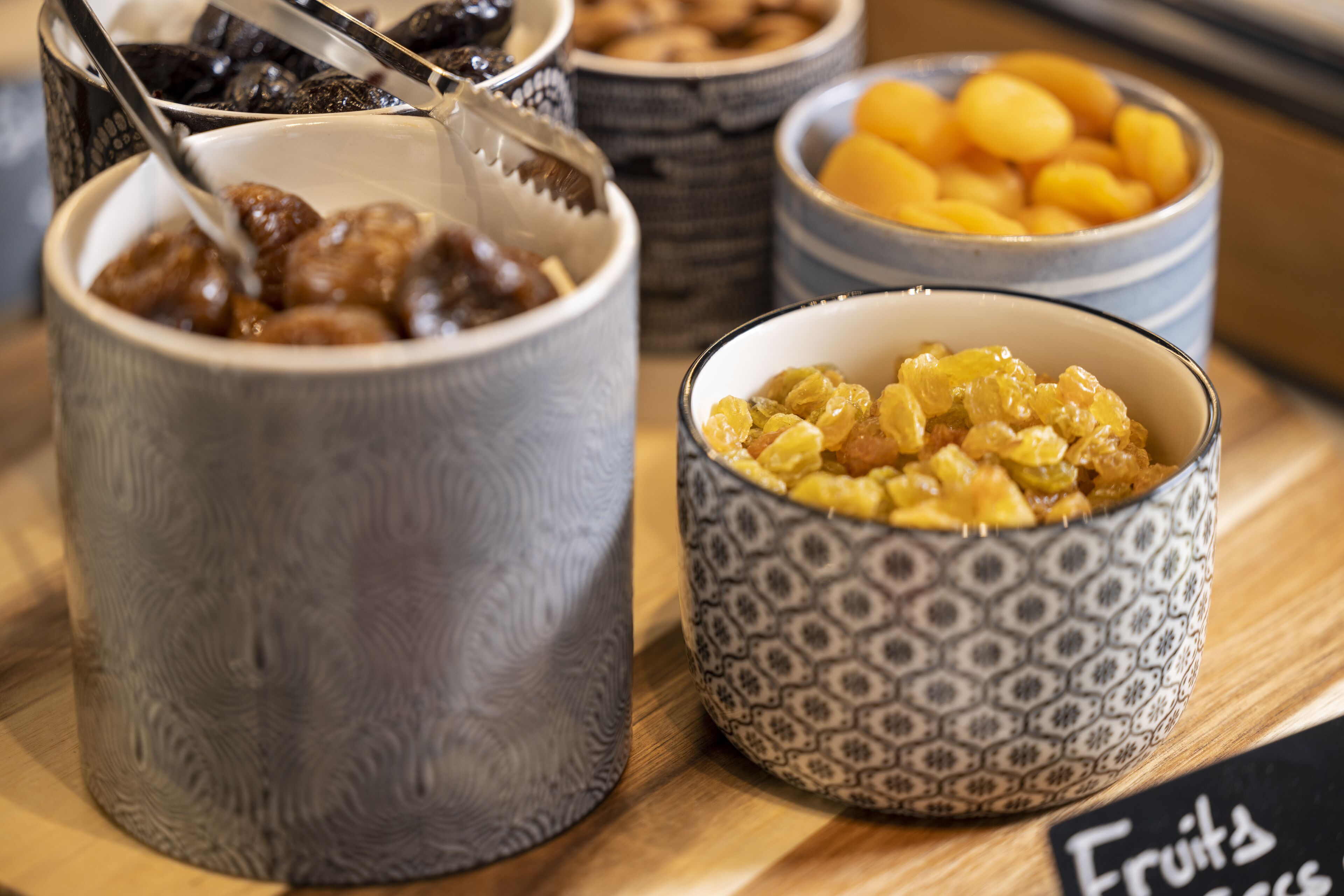 Diversas tigelas com diferentes tipos de alimentos, incluindo frutas e nozes, dispostas sobre uma superfície de madeira.