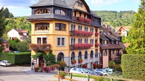 Un edificio de varios pisos con balcones decorados con flores, fachada de piedra y un letrero que indica que es un hotel.