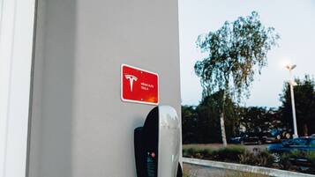 A Tesla charging station mounted on a building with a sign indicating it is for Tesla vehicles.