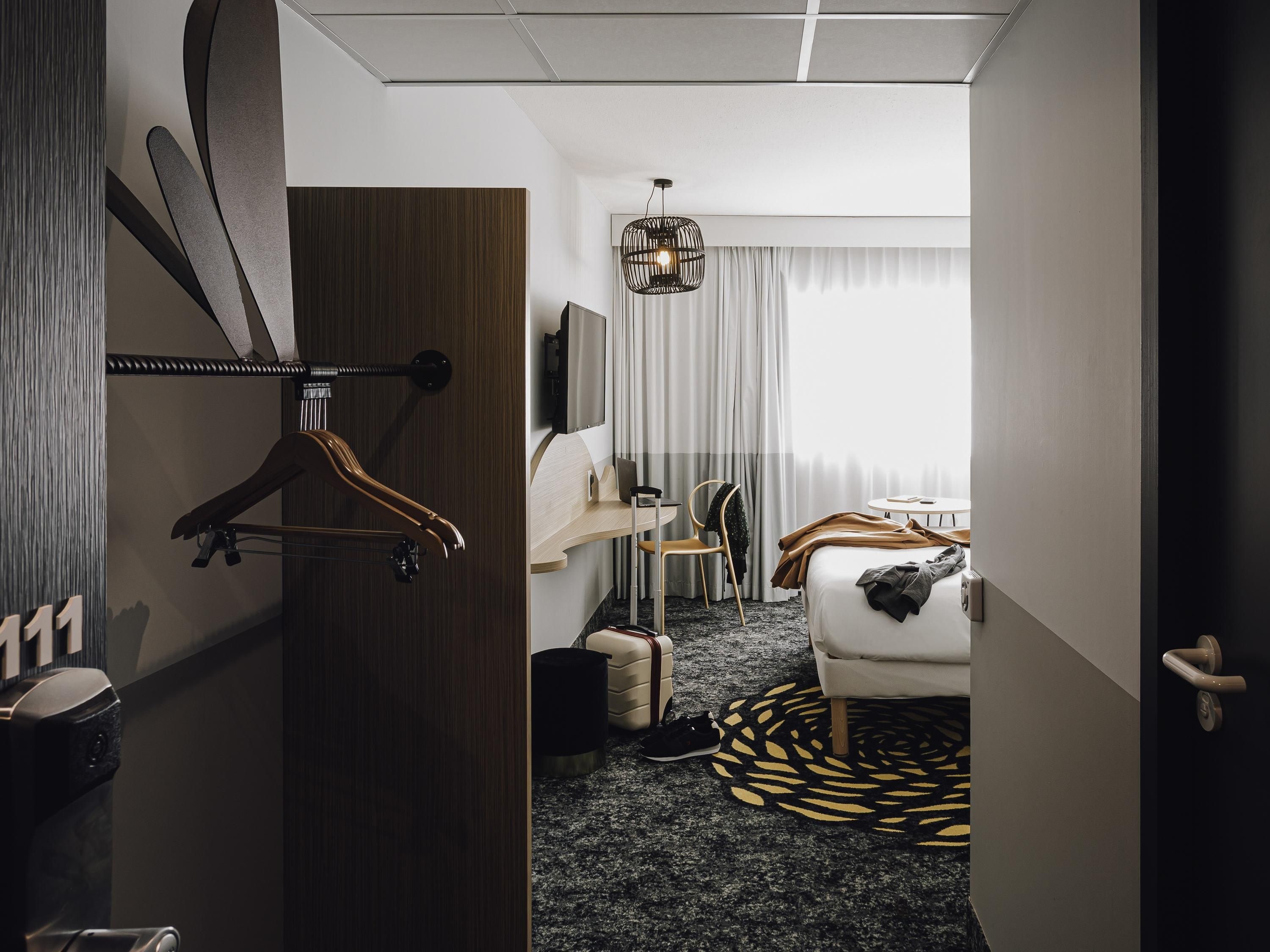 Ein Hotelzimmer mit Bett, Schreibtisch, Stuhl, Kleiderschrank und Badezimmer.