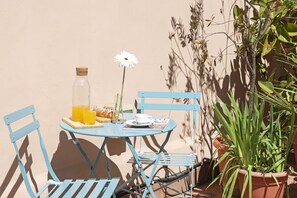 A small outdoor table with a bottle, a flower, and a plate of food. - Parker (Rome)