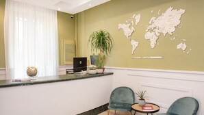 A reception area with a world map on the wall, a laptop on the counter, and two chairs with a small table between them.