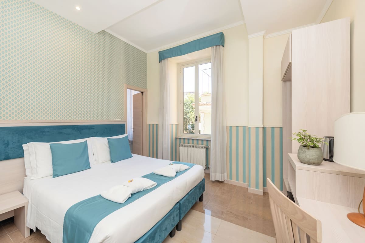 Une chambre d’hôtel avec un lit, une table de chevet et une fenêtre avec des rideaux.