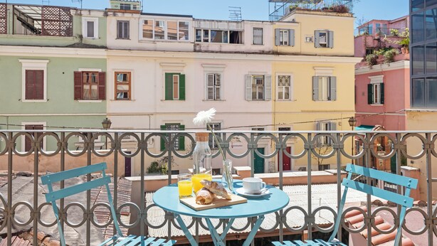 A balcony with a table set for breakfast, overlooking colorful buildings.