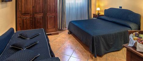 A hotel room with a bed, a desk, a wardrobe, a TV, a lamp, and a framed picture on the wall.