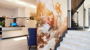 Een moderne lobby met een grote muurschildering, een receptiebalie en een trap.
