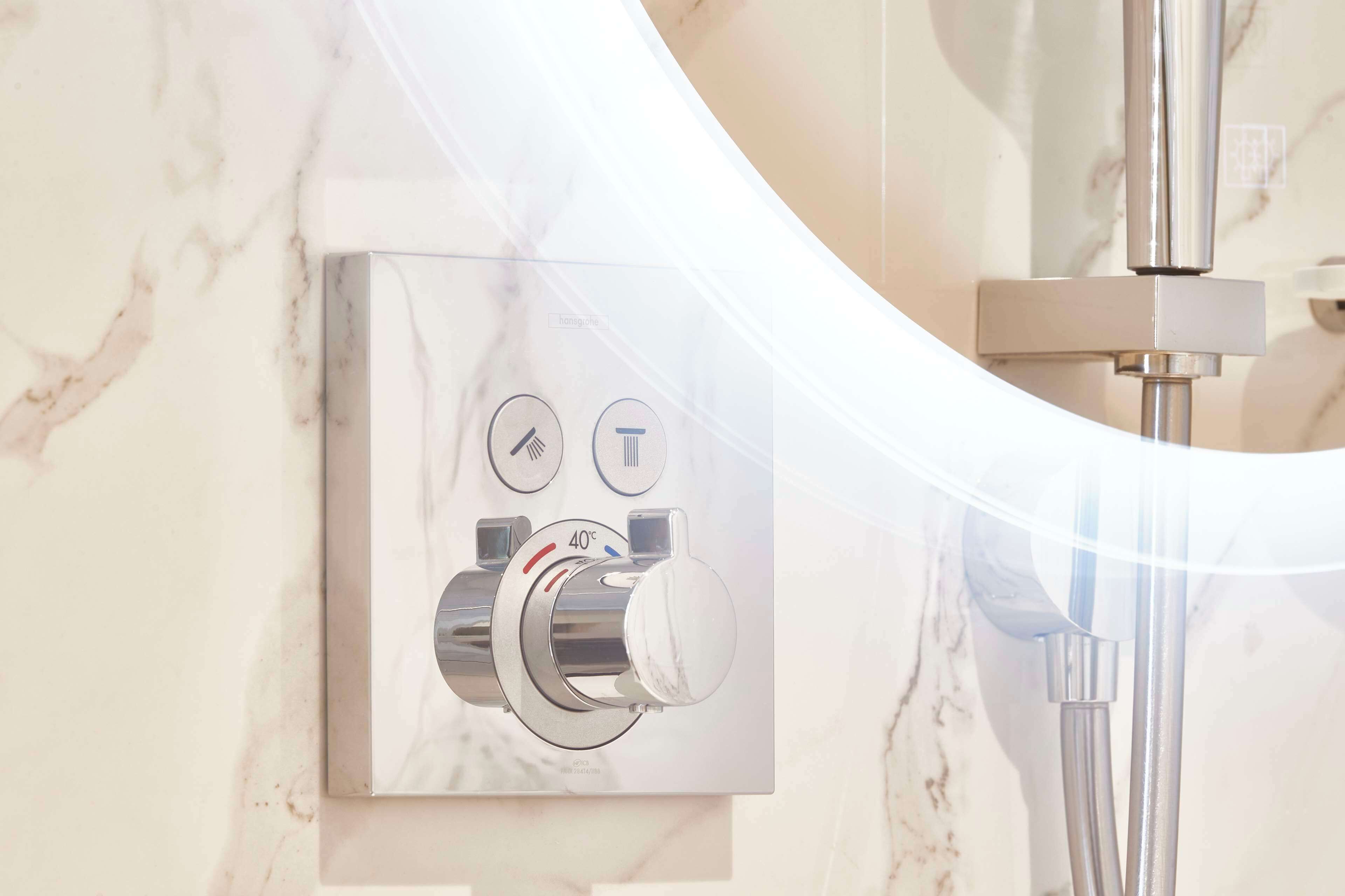 A modern bathroom with a marble wall, a chrome shower control panel, and a chrome showerhead.