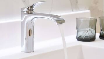 A modern bathroom with a chrome faucet and clear glass candle holders.