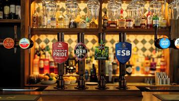 A bar with multiple beer taps and a variety of bottles in the background.