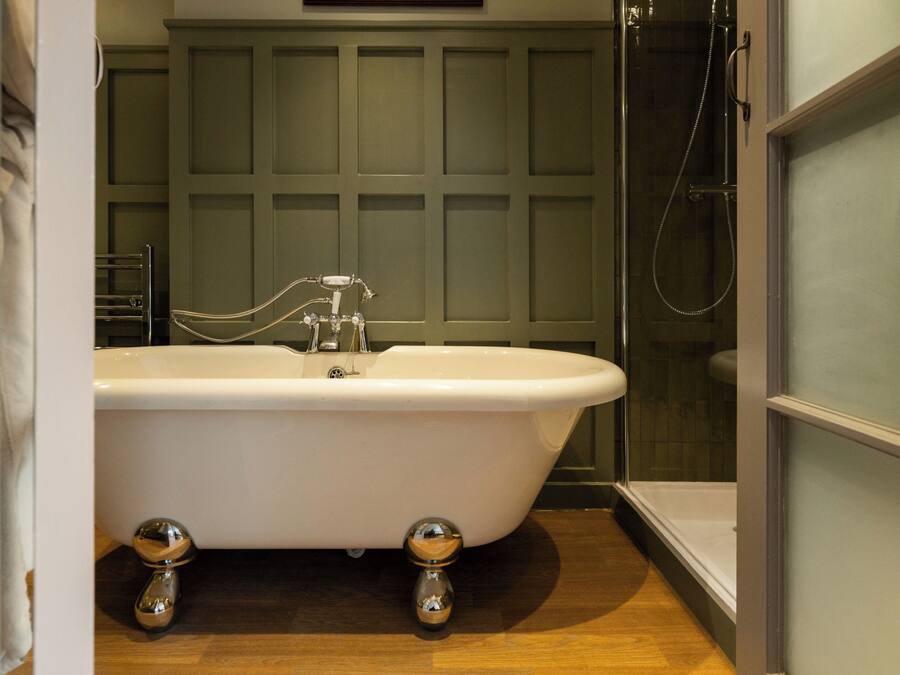 A bathroom with a freestanding bathtub, a shower, and a wooden floor.