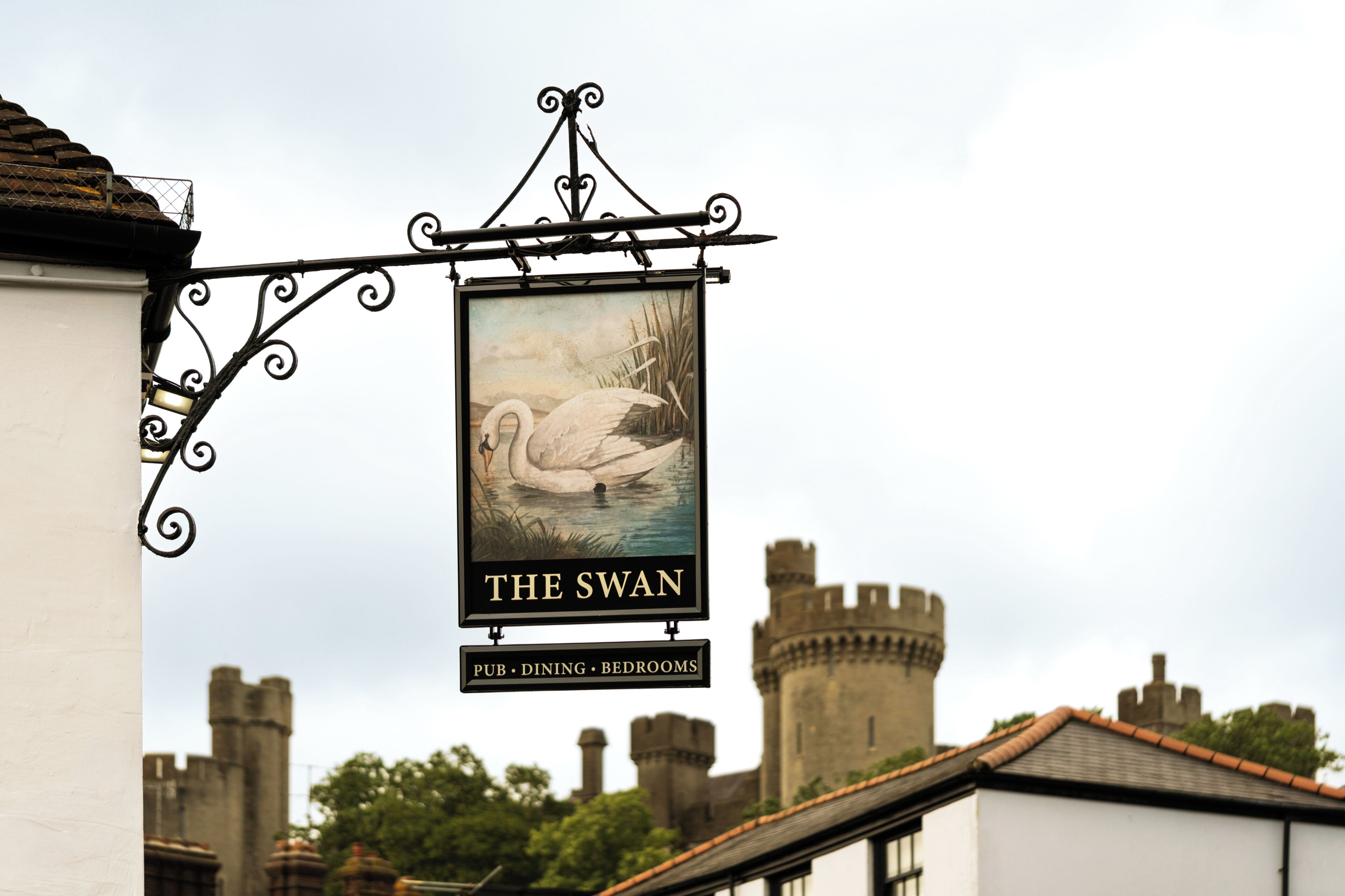 A sign for 'The Swan' pub, dining, and bedrooms with a swan illustration.