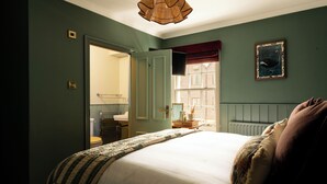 A bedroom with a bed, a window, a radiator, and a mirror. - The Swan (Arundel)