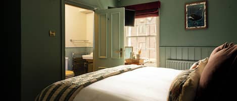 Un dormitorio con cama, ventana, radiador y espejo.
