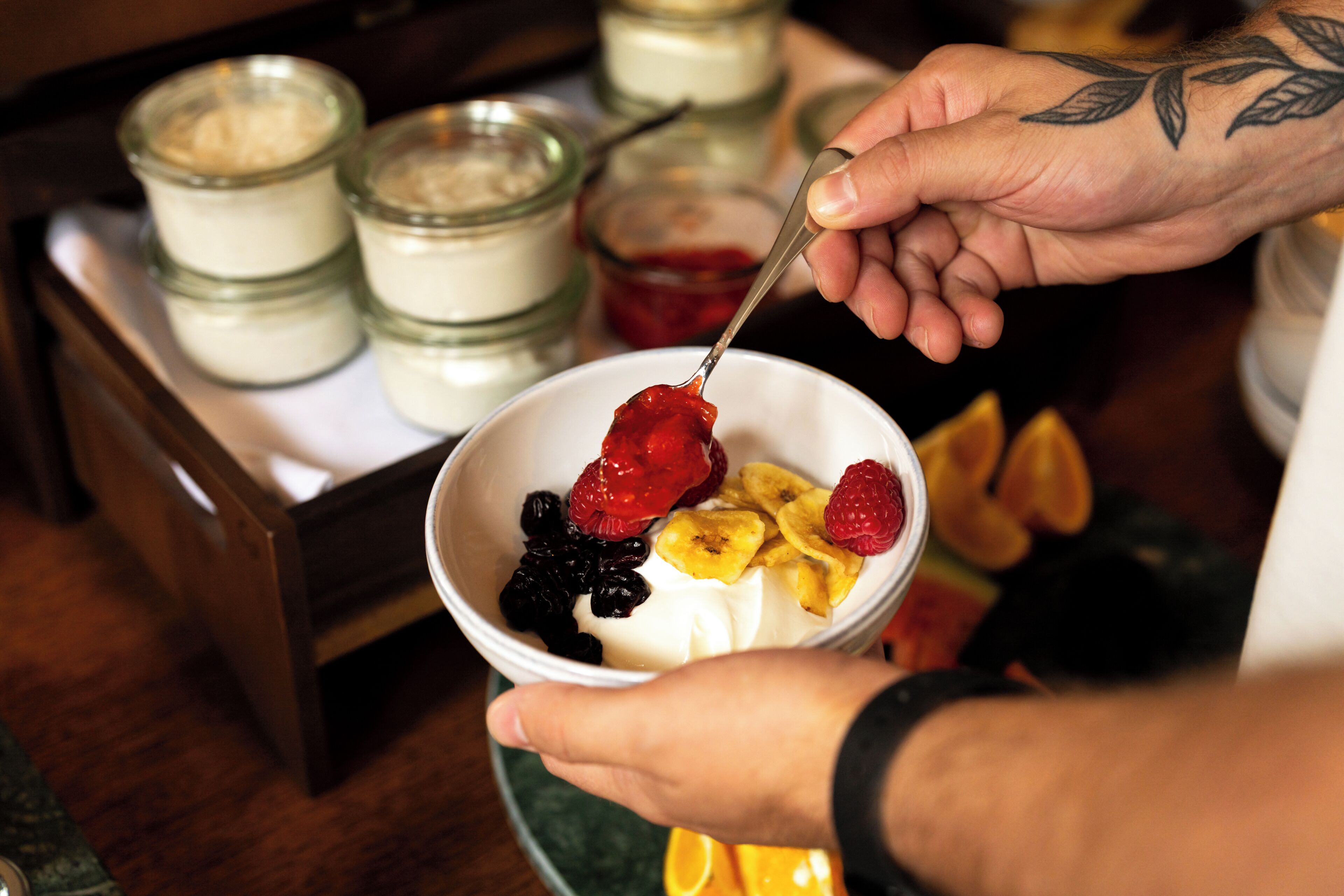 Une personne qui présente un dessert composé de fruits et qui utilise une cuillère pour le servir.