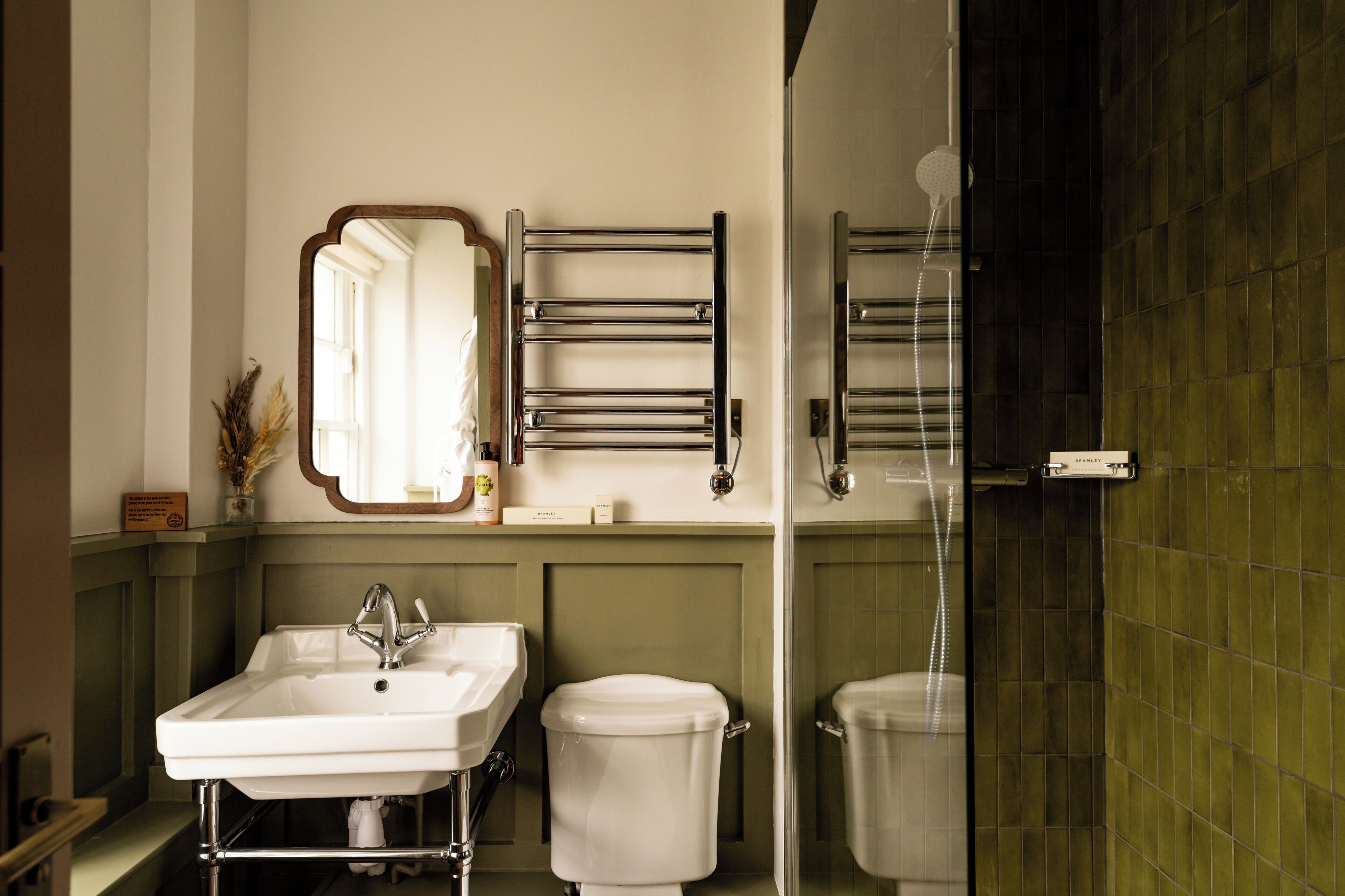 A bathroom with a sink, two toilets, a towel rack, and a mirror.