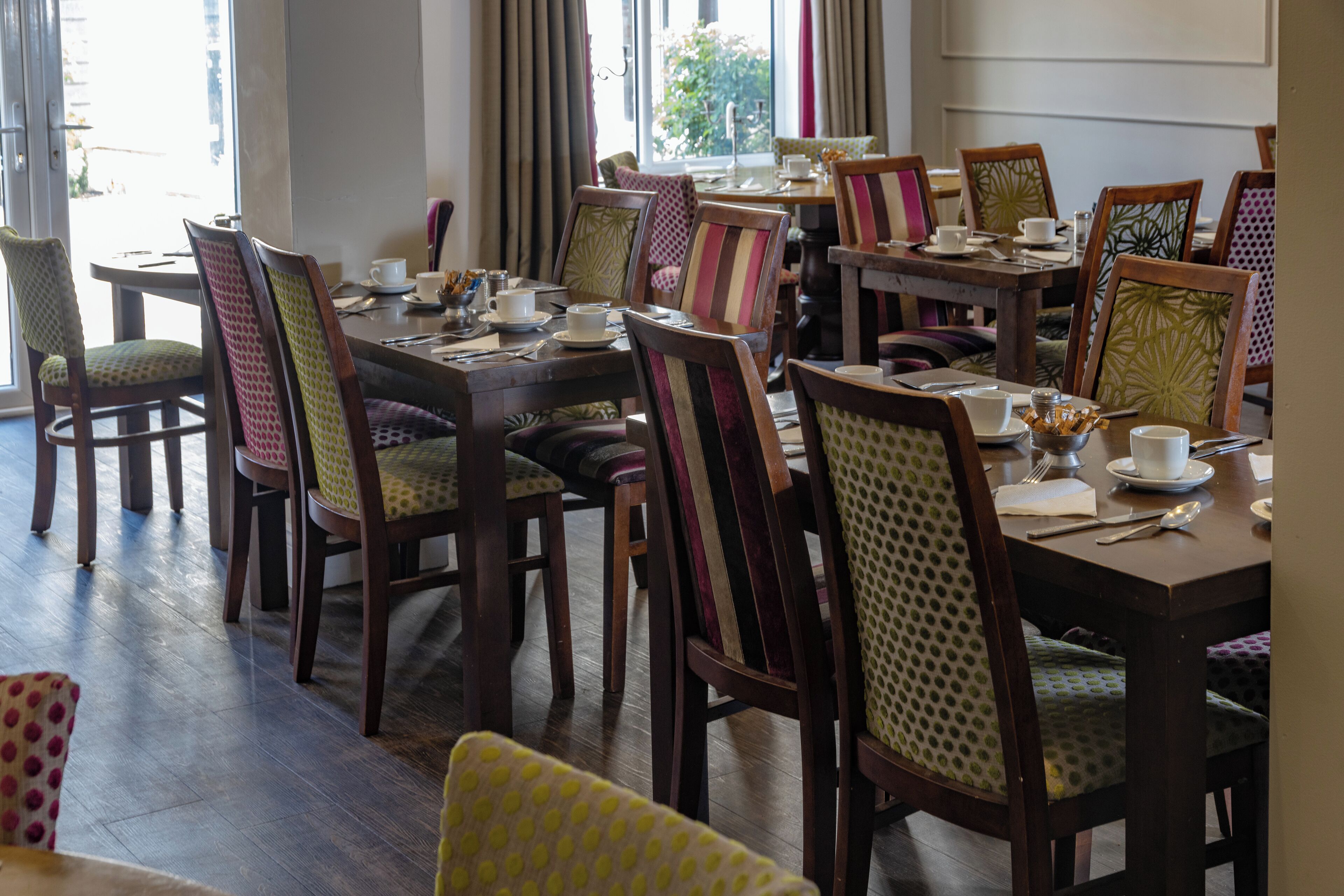 A dining area with multiple tables and chairs, some with patterned upholstery.
