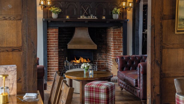 A cozy interior with a brick fireplace, leather seating, and a wooden dining table set for four. - Best Western Brome Grange (Eye)