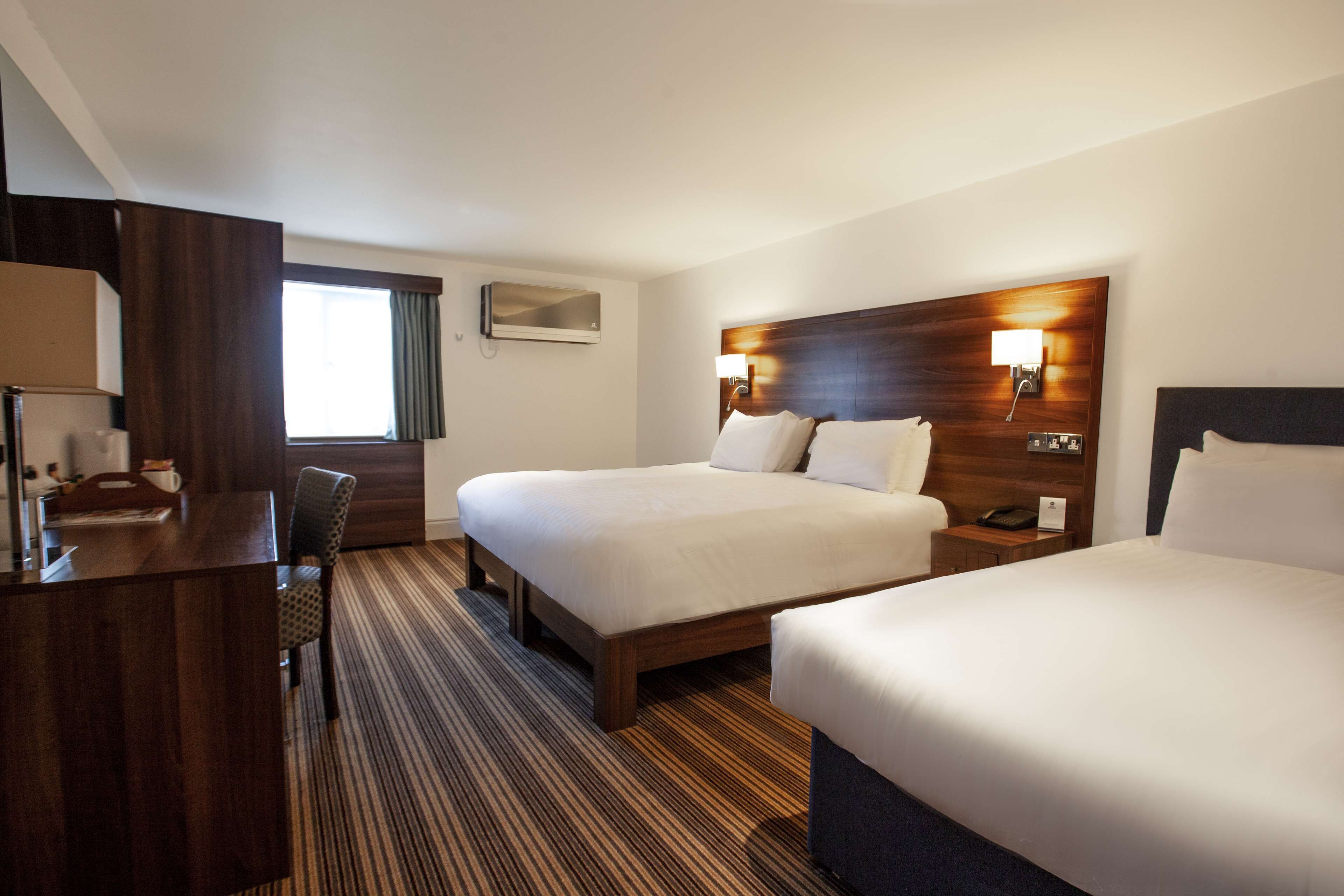 Ein Hotelzimmer mit zwei Betten, einem Schreibtisch und einem Stuhl.