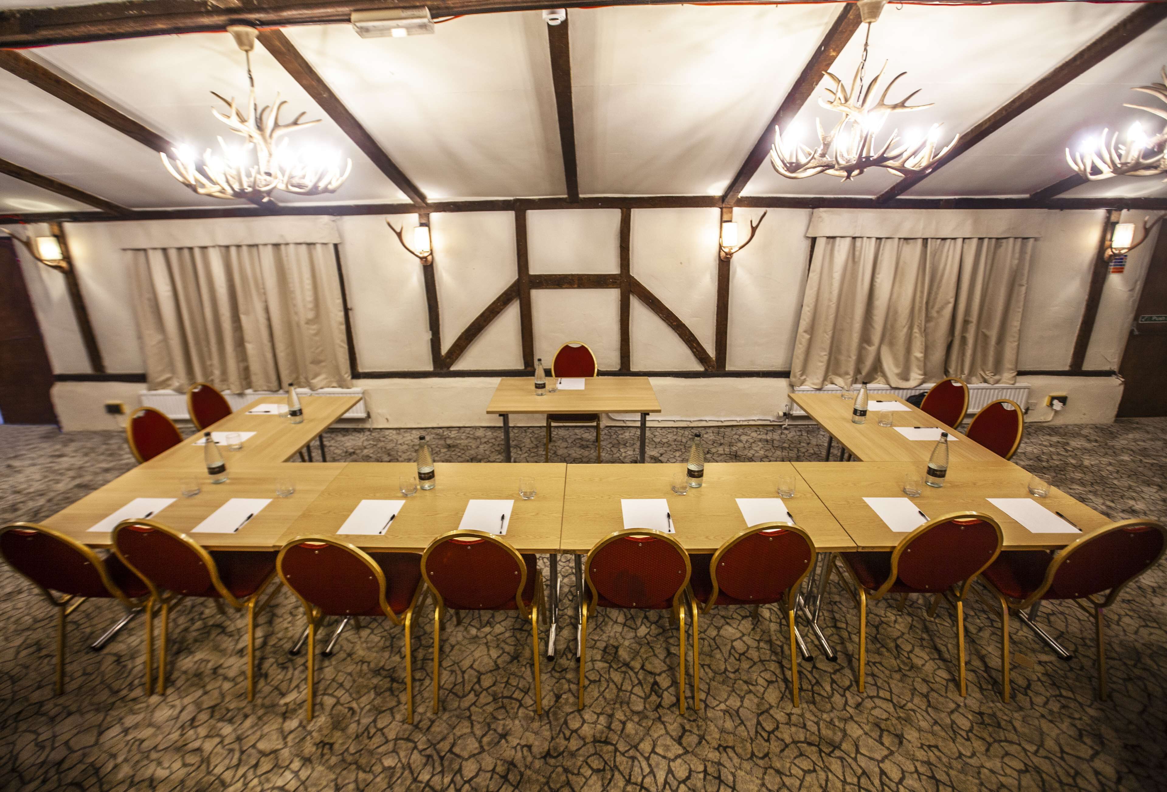 Una sala conferenze con un lungo tavolo, sedie rosse e lampadari.