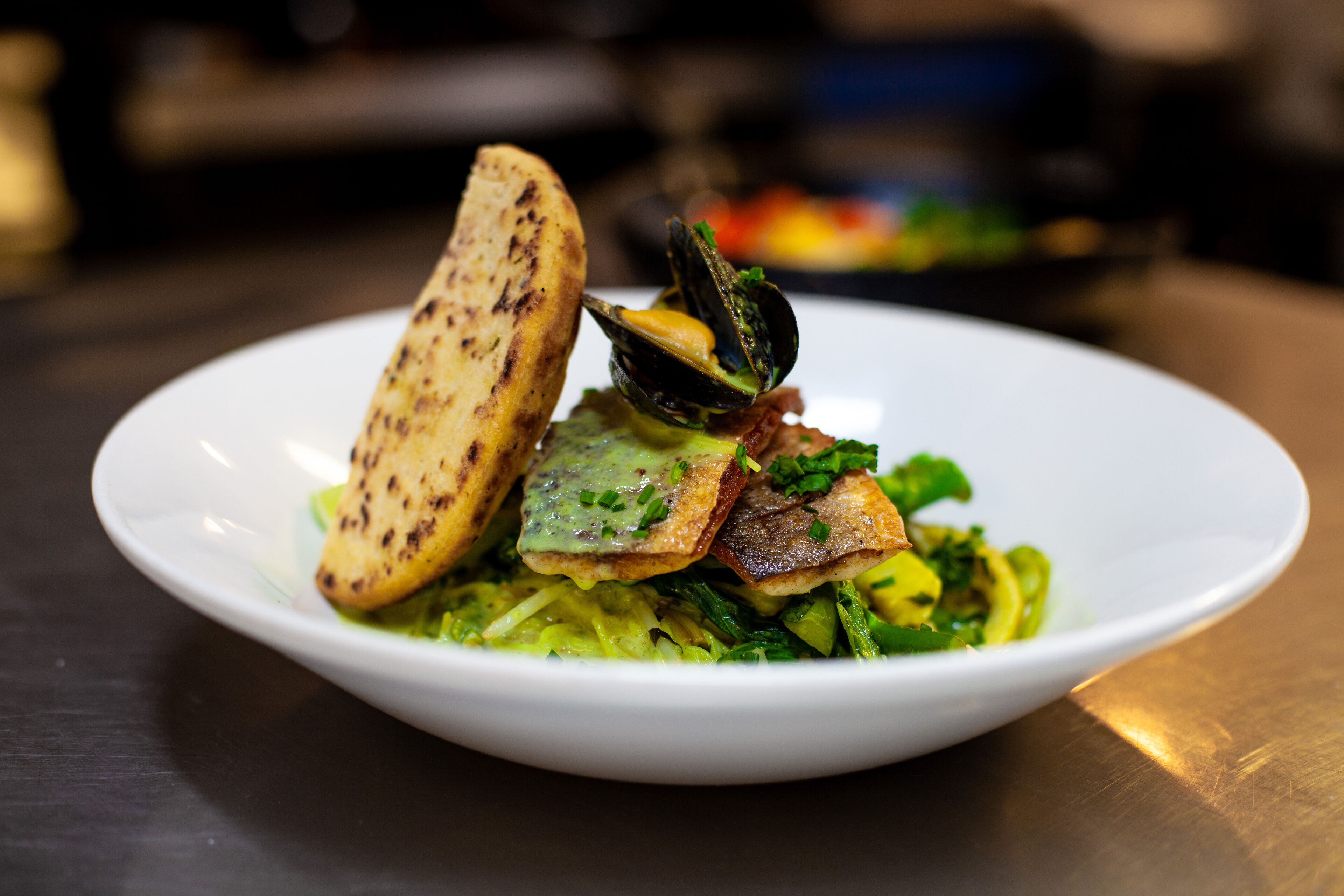 A plate of food with mussels, bread, and greens.