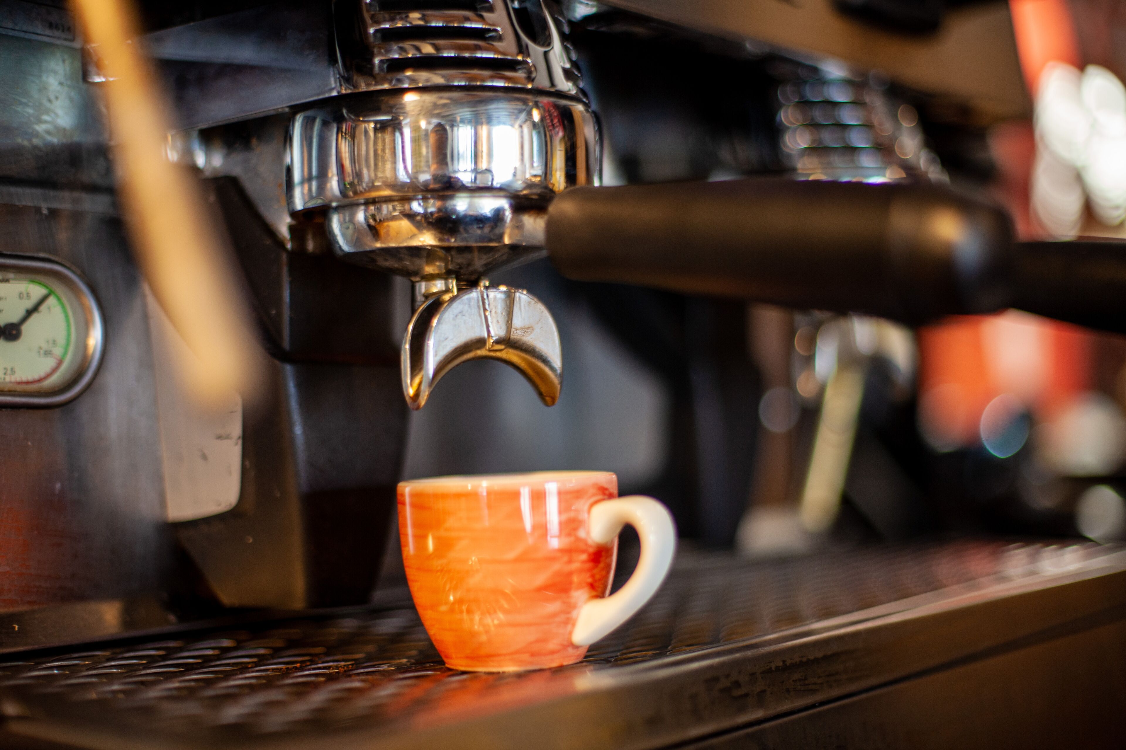 Una cafetera con una taza debajo del pico.