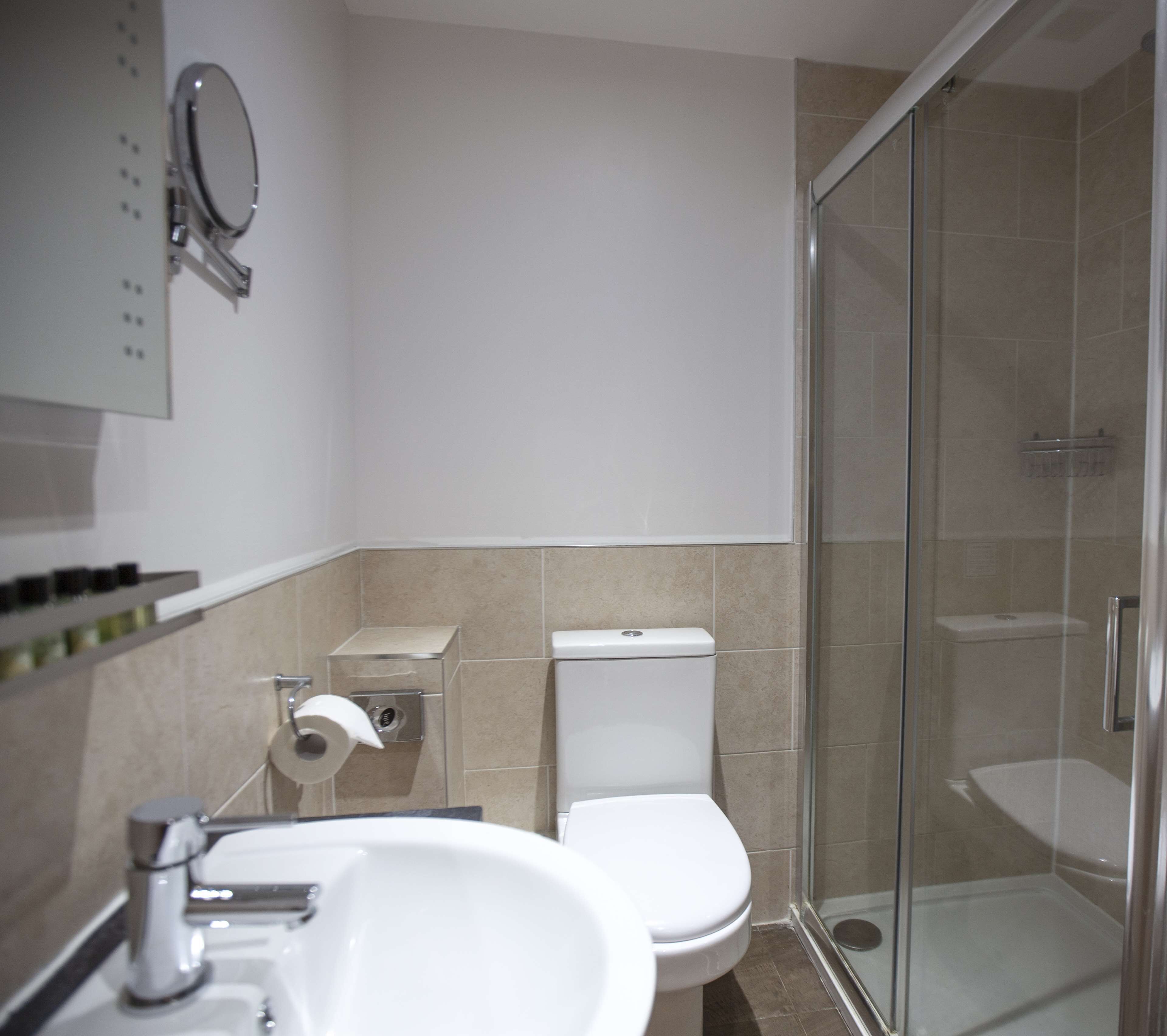A modern bathroom with a glass shower enclosure, a white sink, and a toilet.