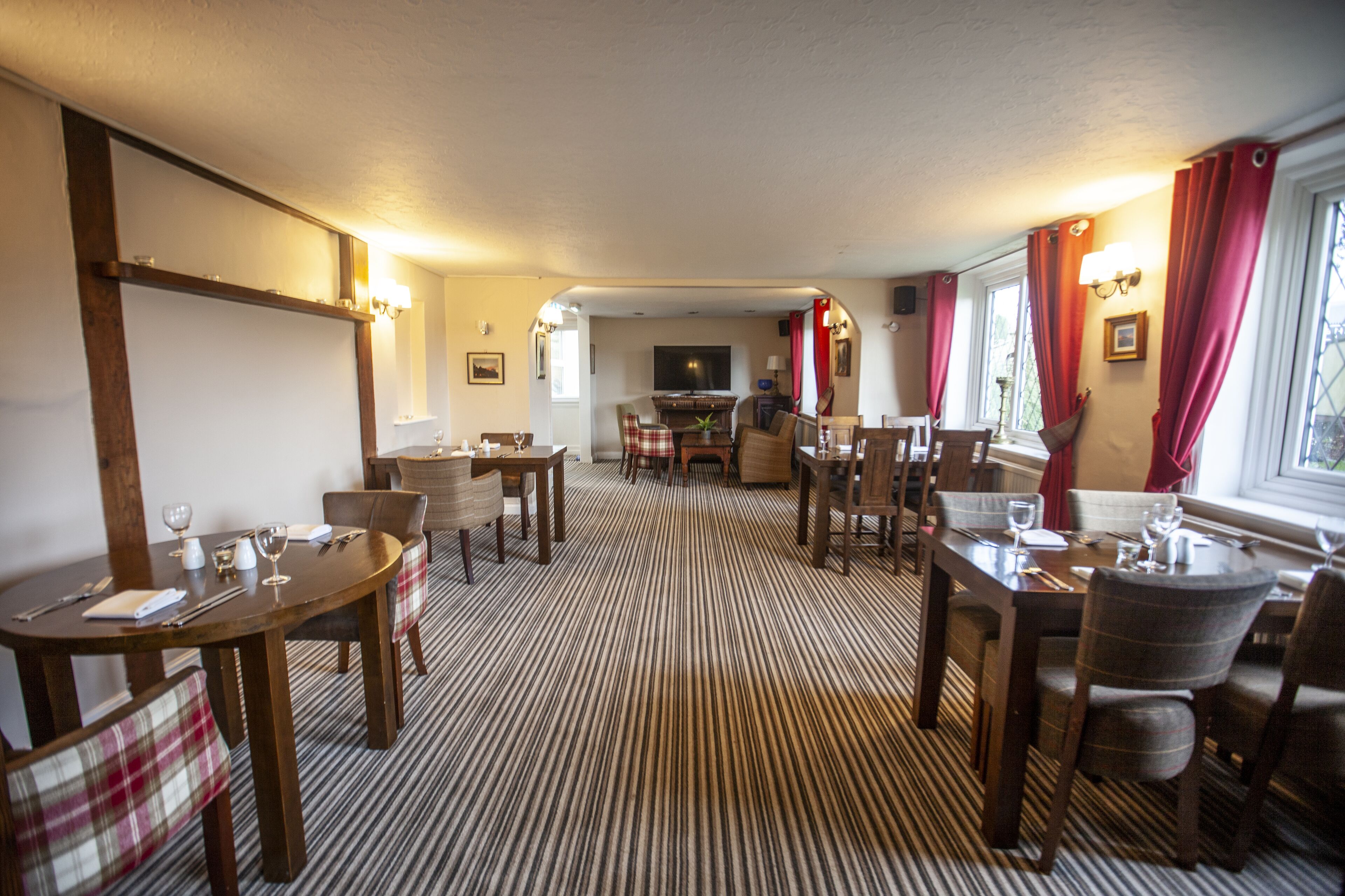 A dining area with striped carpet, wooden tables, and chairs.