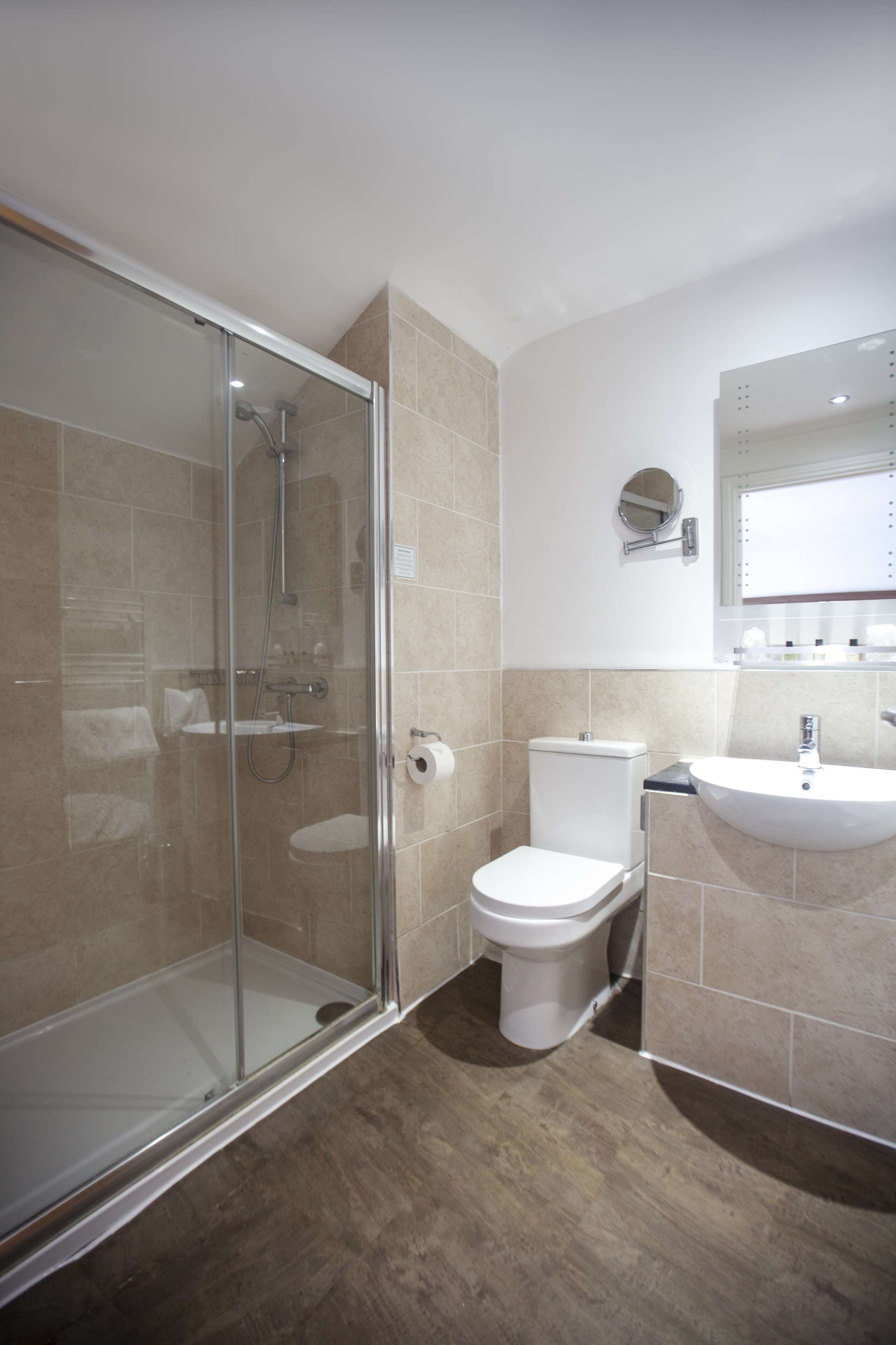 A modern bathroom with a glass-enclosed shower, a toilet, and a sink.