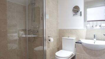 A modern bathroom with a glass-enclosed shower, a toilet, and a sink.