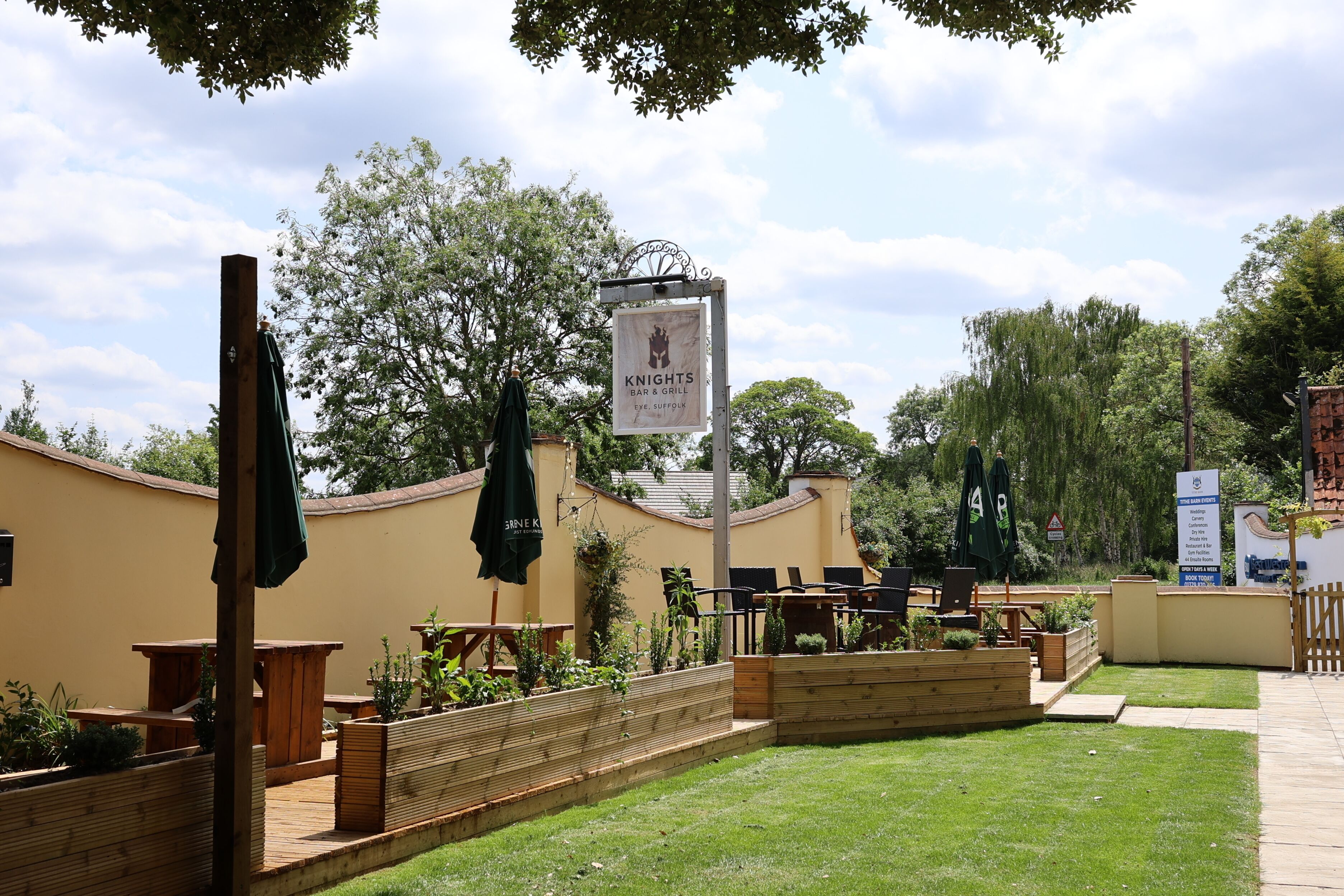 A courtyard with outdoor seating, a sign for Knights Grill Bar & Grill, and a sign for The Barn Events.