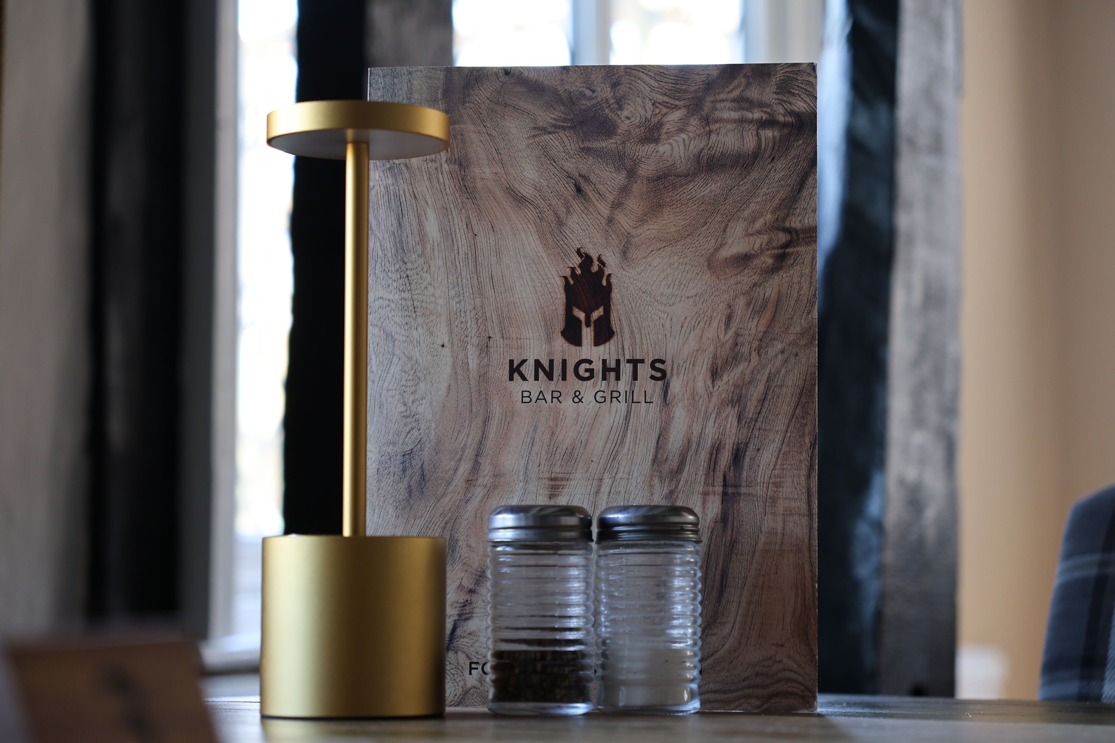 A wooden sign with a logo and text for 'Knights Bar & Grill'.