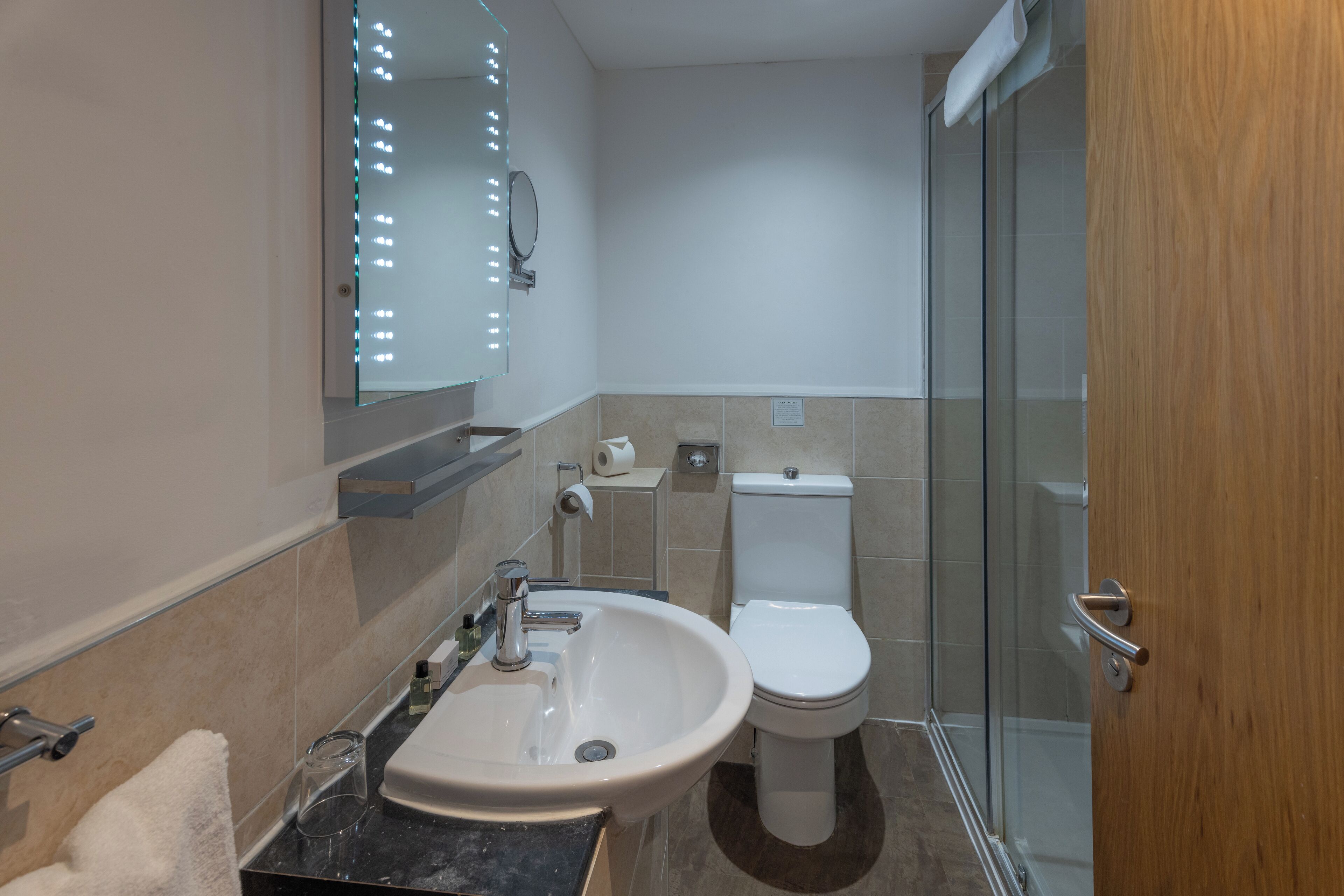 Ein modernes Badezimmer mit Waschbecken, Spiegel, Toilette und Duschkabine aus Glas.