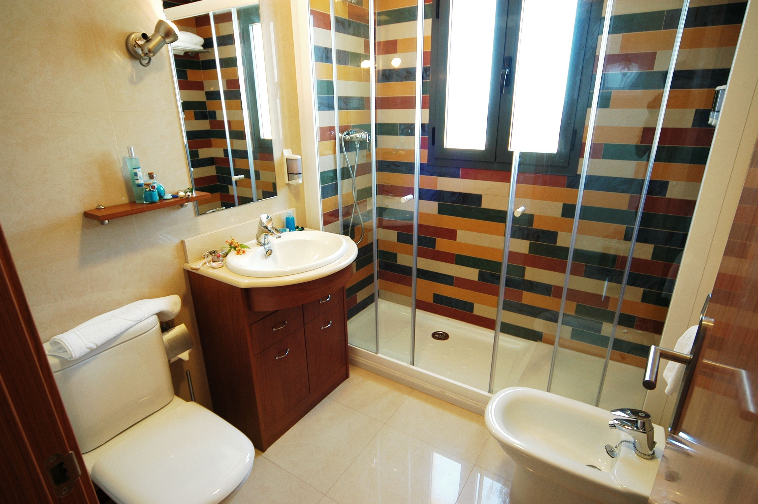 A bathroom with a shower, toilet, sink, and a mirror.