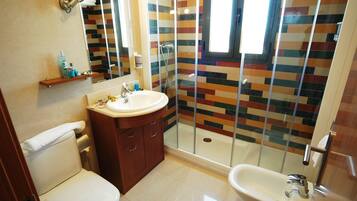 A bathroom with a shower, toilet, sink, and a mirror.