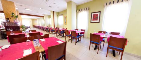 A dining area with multiple tables and chairs, arranged in rows.
