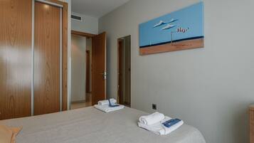 Una habitación de hotel con una cama, un cuadro de una escena de playa y un armario de madera.