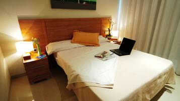 Une chambre d’hôtel avec un lit, une table de chevet, une lampe, un ordinateur portable et un tableau au mur.